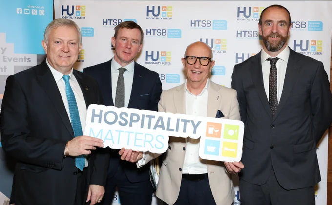 Patsy McGlone MLA, Justin McNulty MLA, Mark H Durkan MLA standing with a representative of #HospitalityMatters event &  holding a 'Hospitality Matters' board.