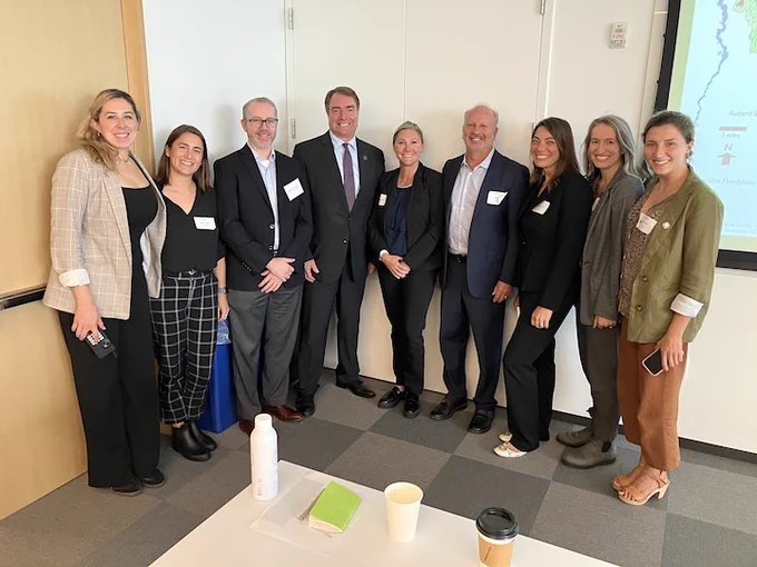 People wearing business attire posing for a photo in a conference room.