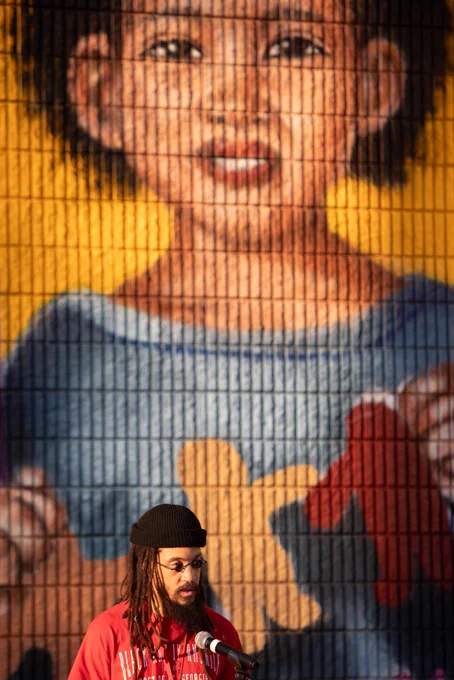 An artist speaks in front of a mural