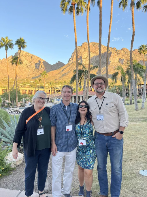 Four people with conference badges in front of a mountain