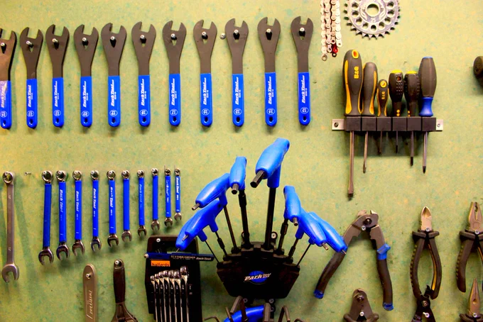 Bicycle tools hanging on a wall. Image used: "Bicycle workshop tools" by Andreas, available at https://www.flickr.com/photos/10978010@N07/6169917260, licensed under CC BY 2.0, https://creativecommons.org/licenses/by/2.0/.