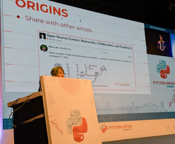 Mars Lee delivering keynote. On the slide is a screenshot of their discussion in the open source design forum about their comics on contributing to open source. My name is at the bottom corner.