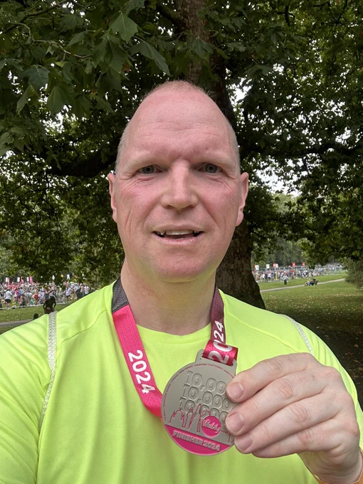 Photograph shows the author in a fluorescent yellow top wearing a Vitality 10K medal