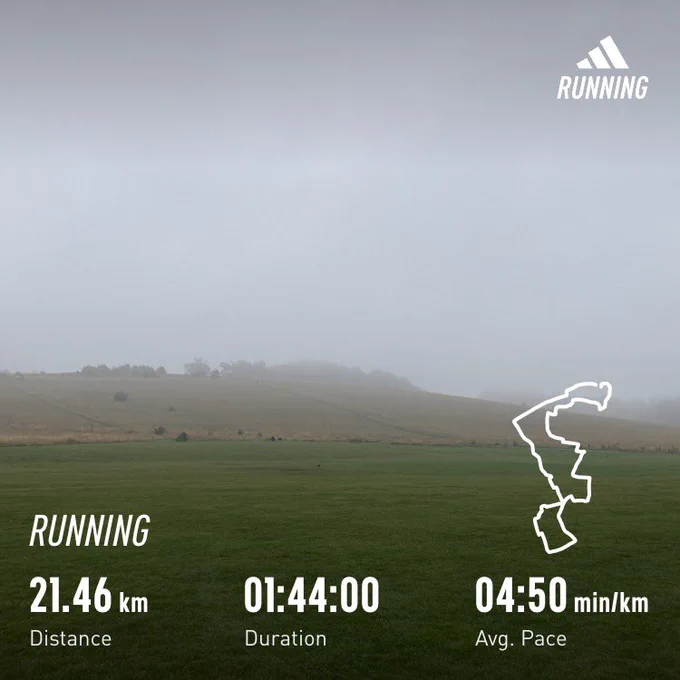 Misty morning view over a grassy field and hills. Running stats superimposed (distance: 21.46km, time: 1:44)