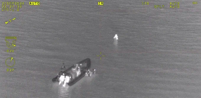 Thermal image of person in water being rescued by coastguard.