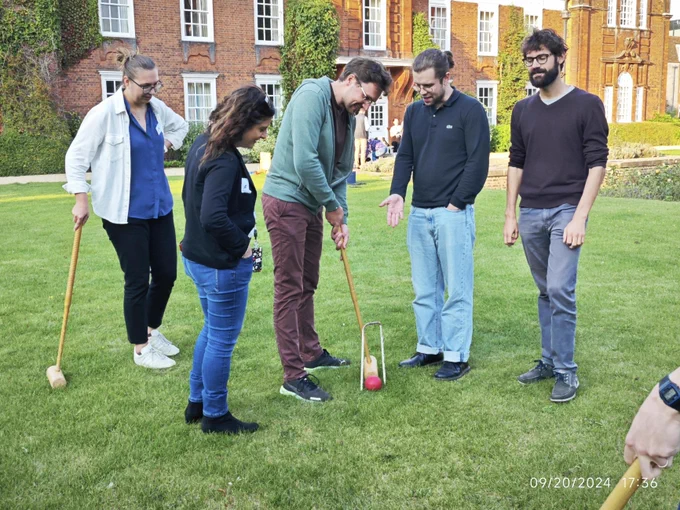 Members of Efficient Study Design theme playing croquet outside on lawn