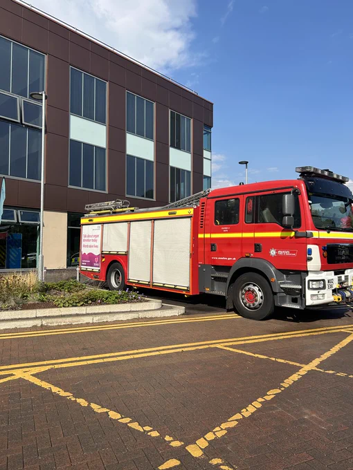 A fire engine is parked outside the Dyson Cancer Centre on a bright sunny day