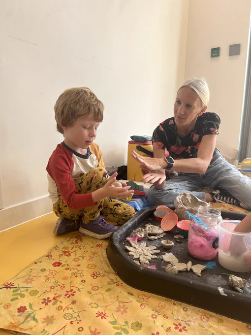A child and nursery worker play with play models