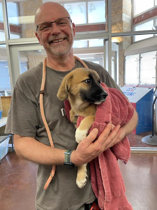 Justin Noel holding a German Shepherd puppy while wearing an ng-conf T-shirt.