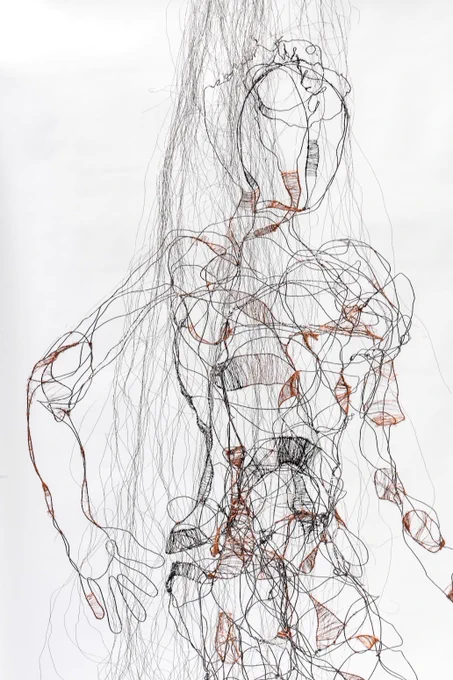 The full metal sculpture of the female figure where the wires are woven in a loose outline, with more dense sections against a white background.