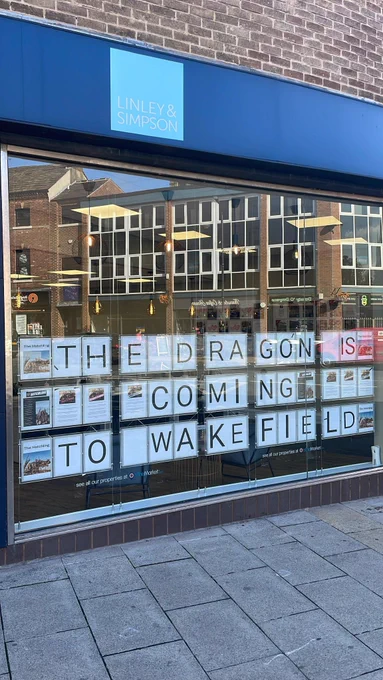 A sign in a window reading “The dragon is coming to Wakefield”