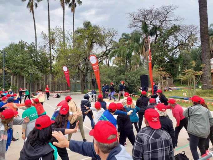 Grupo de personas con gorros de la "Semana del corazón" siguen los pasos de los instructores de actividad física