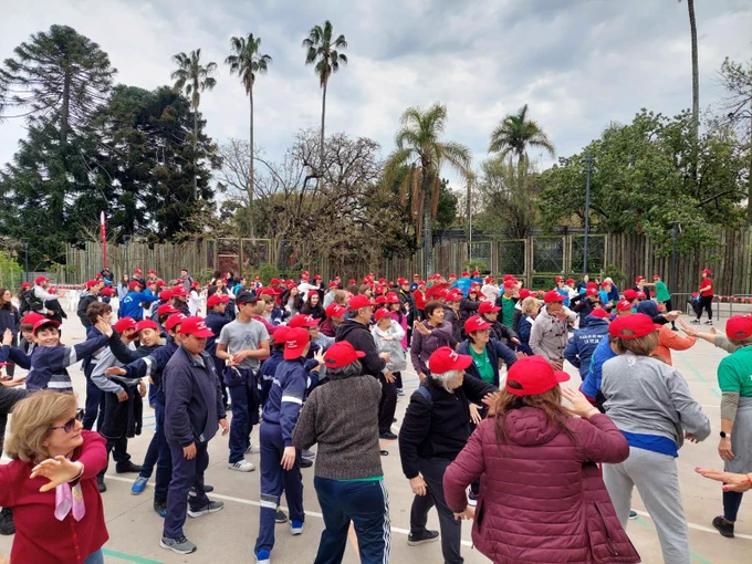 Grupo de personas con gorros de la "Semana del corazón" siguen los pasos de los instructores de actividad física