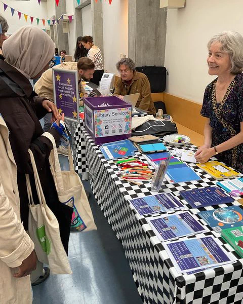 A member of Library Staff greeting students at the Library stall at the Welcome Fair at Aldgate Campus.