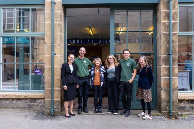 A photograph of 6 people stood smiling outside a historic showroom entrance