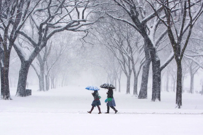 Two people with umbrellas walk through a snow storm at the National Mall in Washington, D.C.  