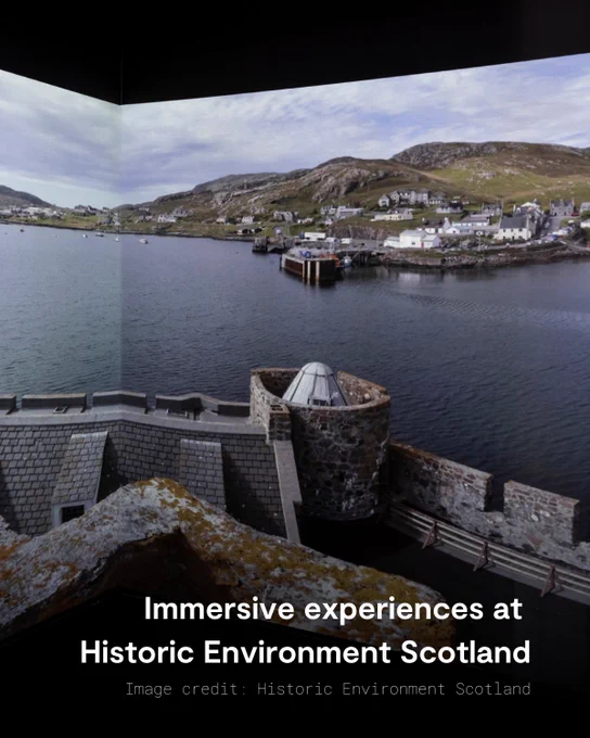 Photo of Historic Environment Scotland's Immersive Cube. This 3m squared space displays 360-degree imagery in an audio-visual exhibition. The cube shows a view from standing on the top of Kismul Castle, on the Isle of Barra, looking out across the bay. 
Text reads: Immersive experiences at Historic Environment Scotland
Image credit: Historic Environment Scotland