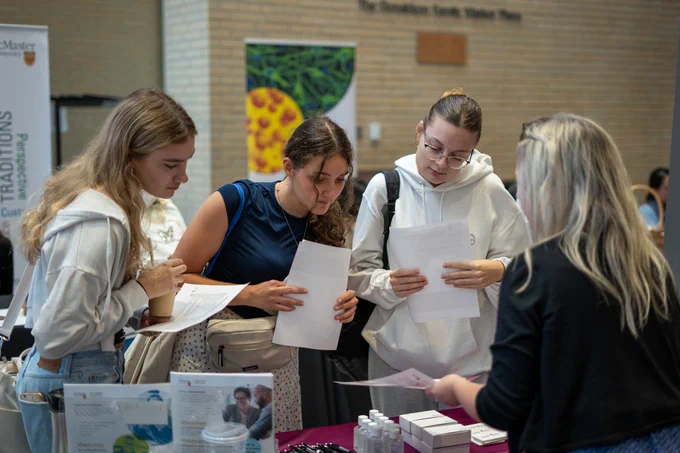 Students looking at program details at a table booth at the fair