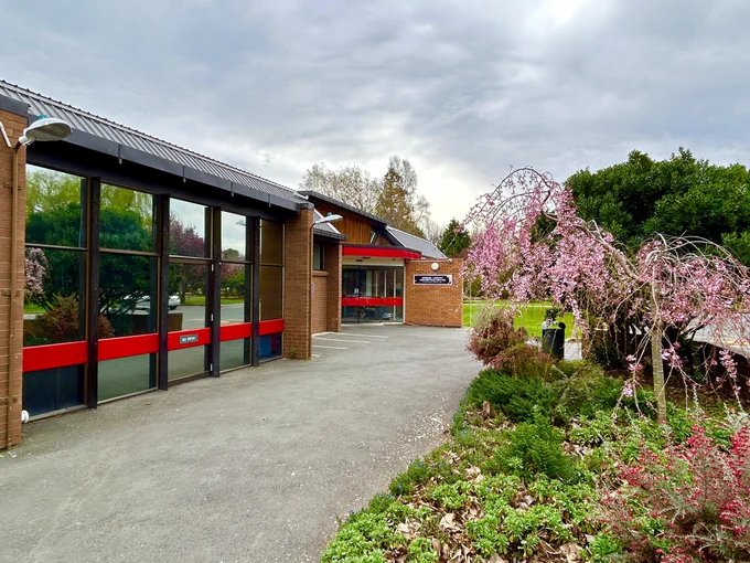 Side angle of entrance to Mosgiel Library, featuring blossom trees in the garden