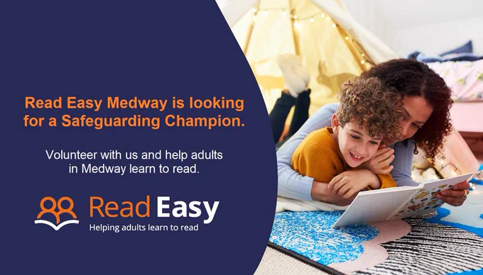 A woman and a small boy lying on a blue patterned rug, reading a book together. She is wearing a pale blue jumper and he is wearing an orange jumper. Text on the right hand side of the image reads "Read Easy Medway is looking for a Safeguarding Champion. Volunteer with us and help adults in Medway learn to read." The Read Easy UK logo is underneath the text.
