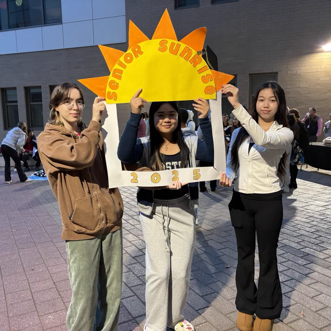 Three students hold up a sign that says "Senior Sunrise 2025