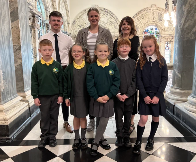 Image of eight people – Damon Henry (CRIS Buddy Up! Project Coordinator), Junior Minister Aisling Reilly, Lisa Dietrich (CEO, CRIS), Bunscoil Bheann Mhadagáin pupils Shane, Rioghnach and Aoibhe, and Cliftonville Integrated Primary School pupils Ultan and Jorgie.
