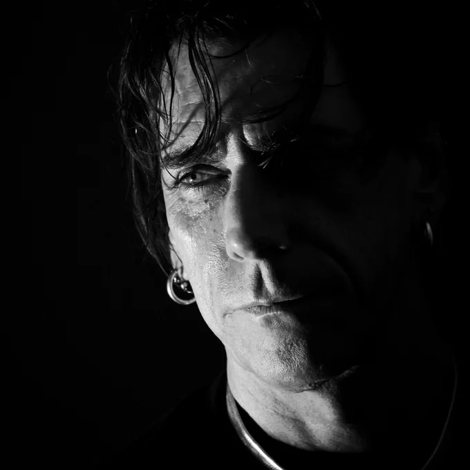 Black and white close-up of artist and writer Andrea Pagnes (VestAndPage), gazing into the distance with shadowed lighting. 