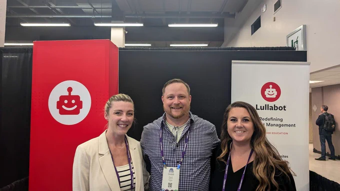 Three people standing in the Lullabot booth, with Lullabot signage behind them