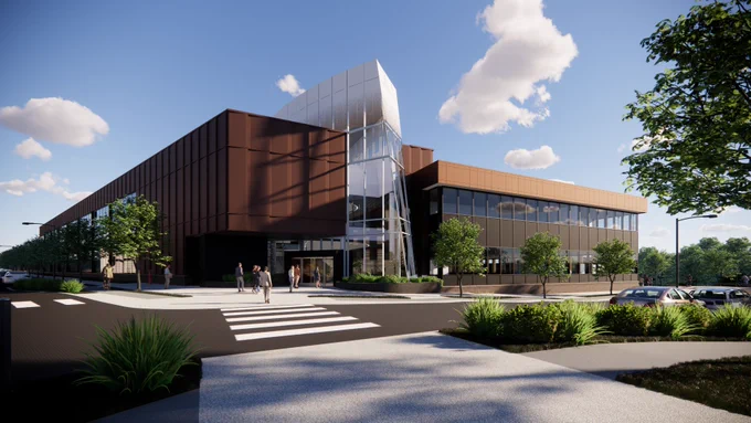 Rendering of a modern two-story building with angular design features and a reflective glass entrance. The structure is surrounded by landscaped areas with trees and a parking lot, with several people walking near the entrance.