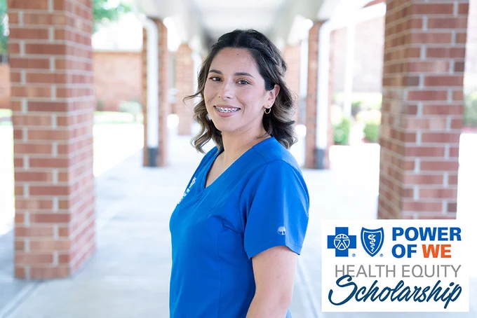 Female wearing blue scrubs outside brick building. Blue Cross Blue Shield logos Power of We Health Equity Scholarship