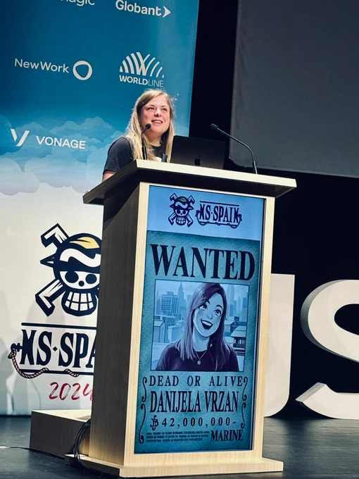 A woman on stage at a conference speaking in front of a microphone