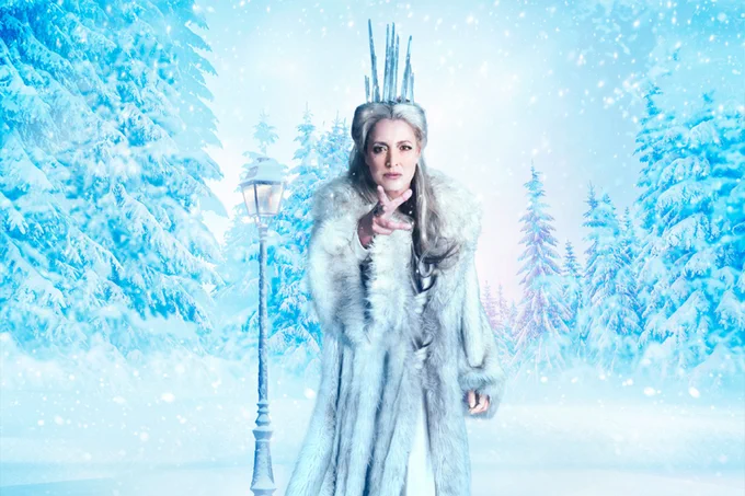 Katy Stephens as the White Witch in front of a wintery forest and lampost background