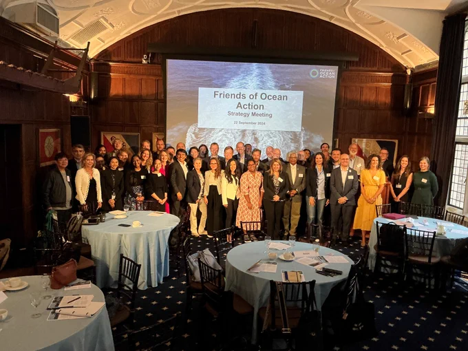 Group of people at the Friends of Ocean Action strategy meeting in an elegant room with a presentation screen displaying the event's title.