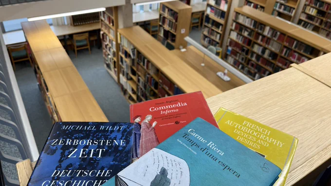 A selection of MMLL Library books in red, yellow, blue and green colours, looking down onto the desks and bookcases on the first floor of the MMLL Library.