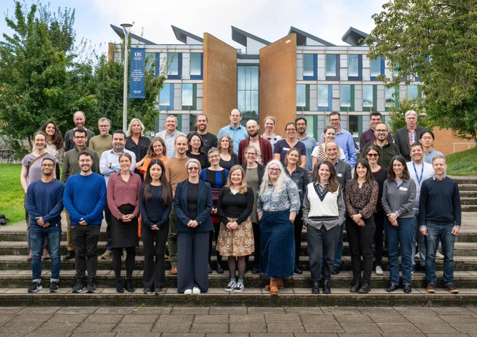 Group picture of the EDRC group standing in front of the University of Sussex Business School.