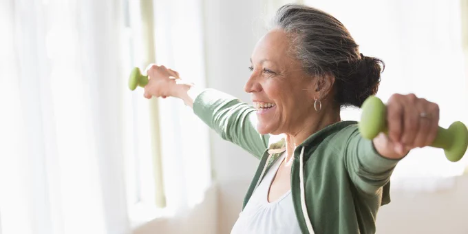 Older woman lifting weights in living room