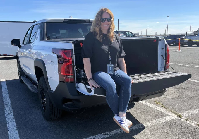 State Efficiency and Environmental Performance Director Hanna Waterstrat sitting on the tailgate of an electric Chevy Silverado.