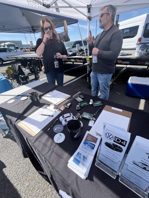 Two people a sponsors table with informational materials.