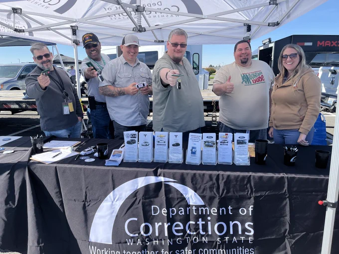 Event sponsors handing out car keys and informational materials from Department of Corrections booth. 
