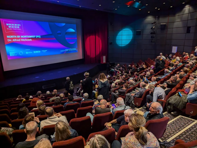 Audience looking at a screen in Pictureville Cinema, with a slide for North by Northwest