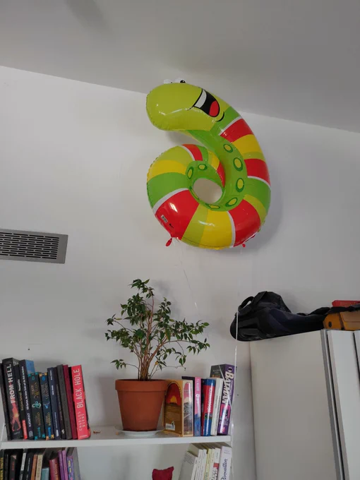 Ein Luftballon in Form eines fröhlich dreinguckenden Wurms, der an der Decke schwebt 