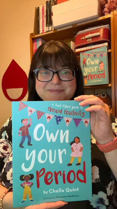 Period Positive founder Chella Quint OBE holding her book Own Your Period while smiling at the camera.