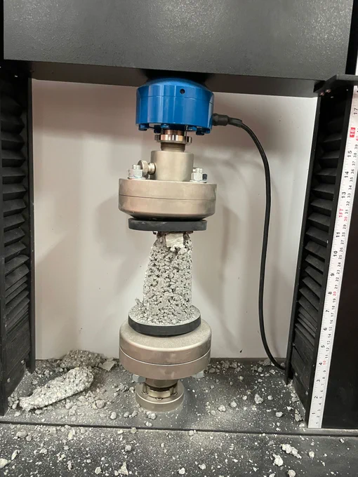 A machine like a hydraulic press crushes a concrete sample
