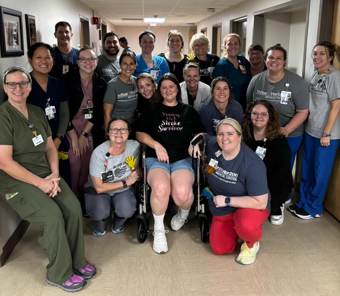 Large group of rehabilitation nurses and therapists gathers around Joanna on her discharge day