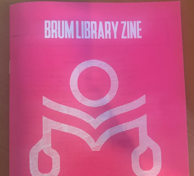 The front cover of 'Brum Library Zine' featuring a cartoon figure reading a book against a pink background.