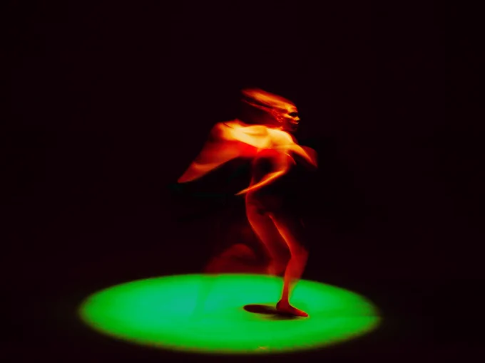 A dancing figure illuminated against a dark background