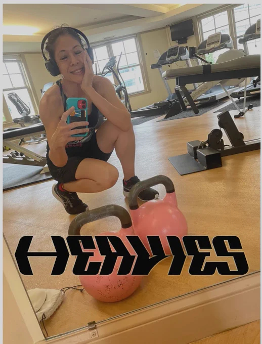 Happy woman with kettlebells - text = Heavies