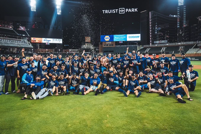 A group photo of the Kansas City Royals on the field at Truist Park celebrating a postseason berth.