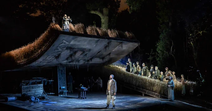 The Fiddler on the Roof set. Chava stands on the roof amongst the wheat playing the clarinet. At the centre of the stage is Tevye. Behind him amongst the wheat are the rest of the cast watching. 