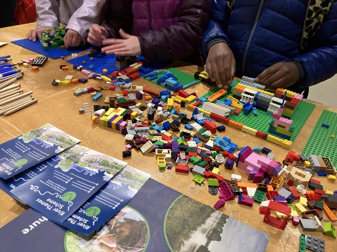 Children using a table full of building blocks to create flood defence designs for homes, gardens and playgrounds.